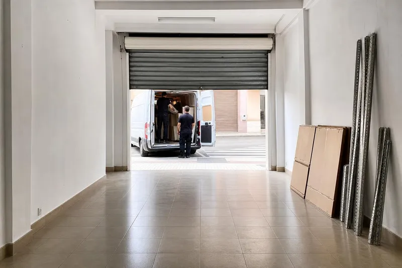 Local comercial vacío y barrido, con la persiana a medio subir